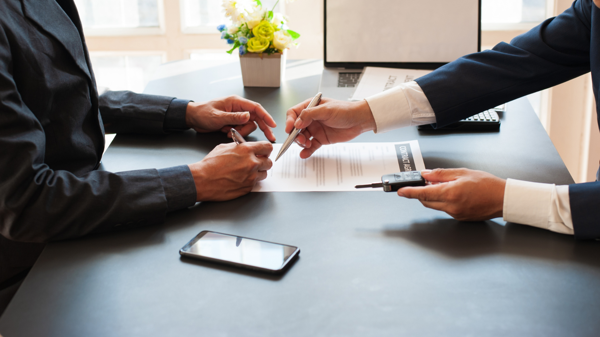 A man and a woman are sitting at a table signing a contract.