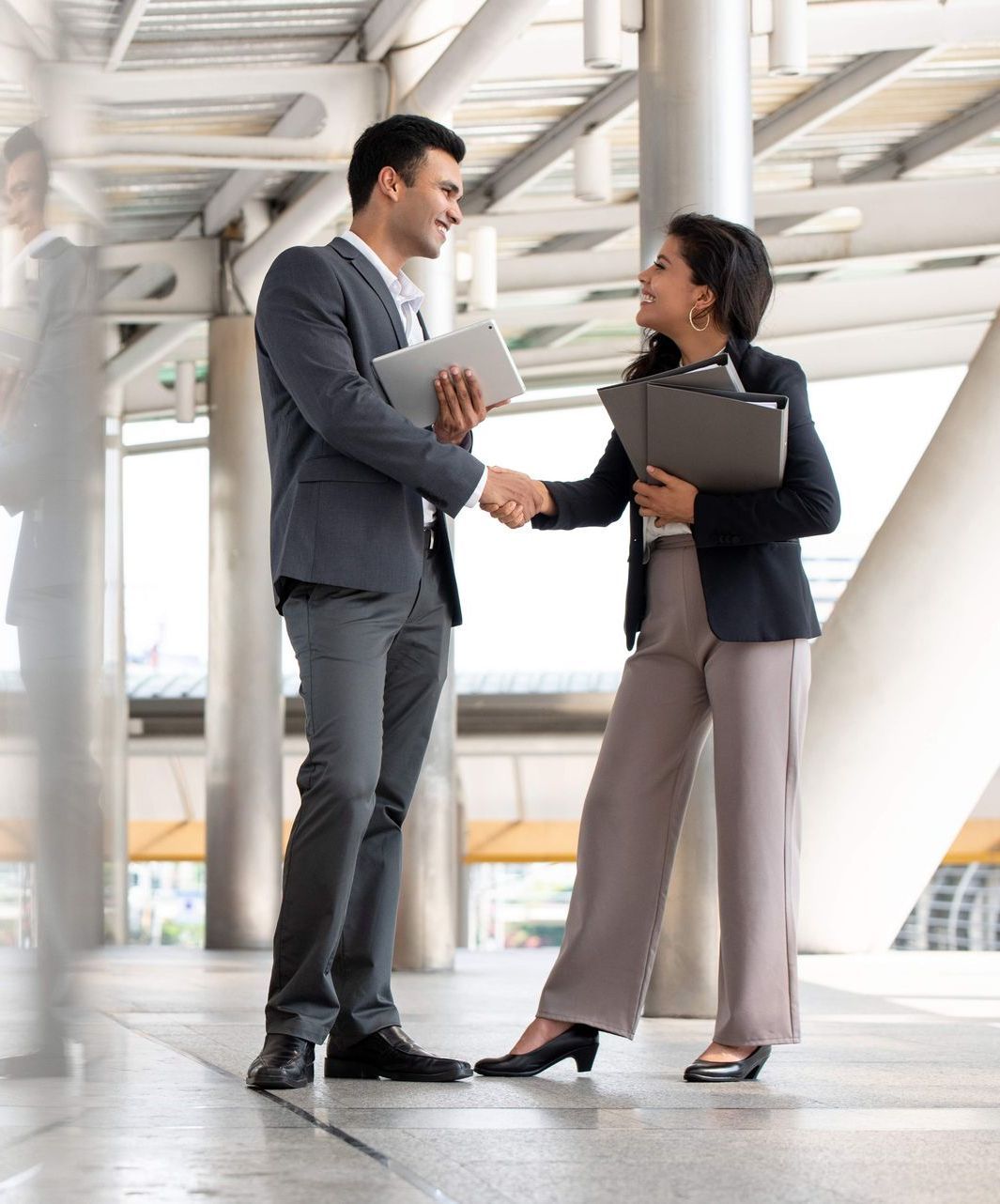 A man and a woman are shaking hands while standing next to each other.