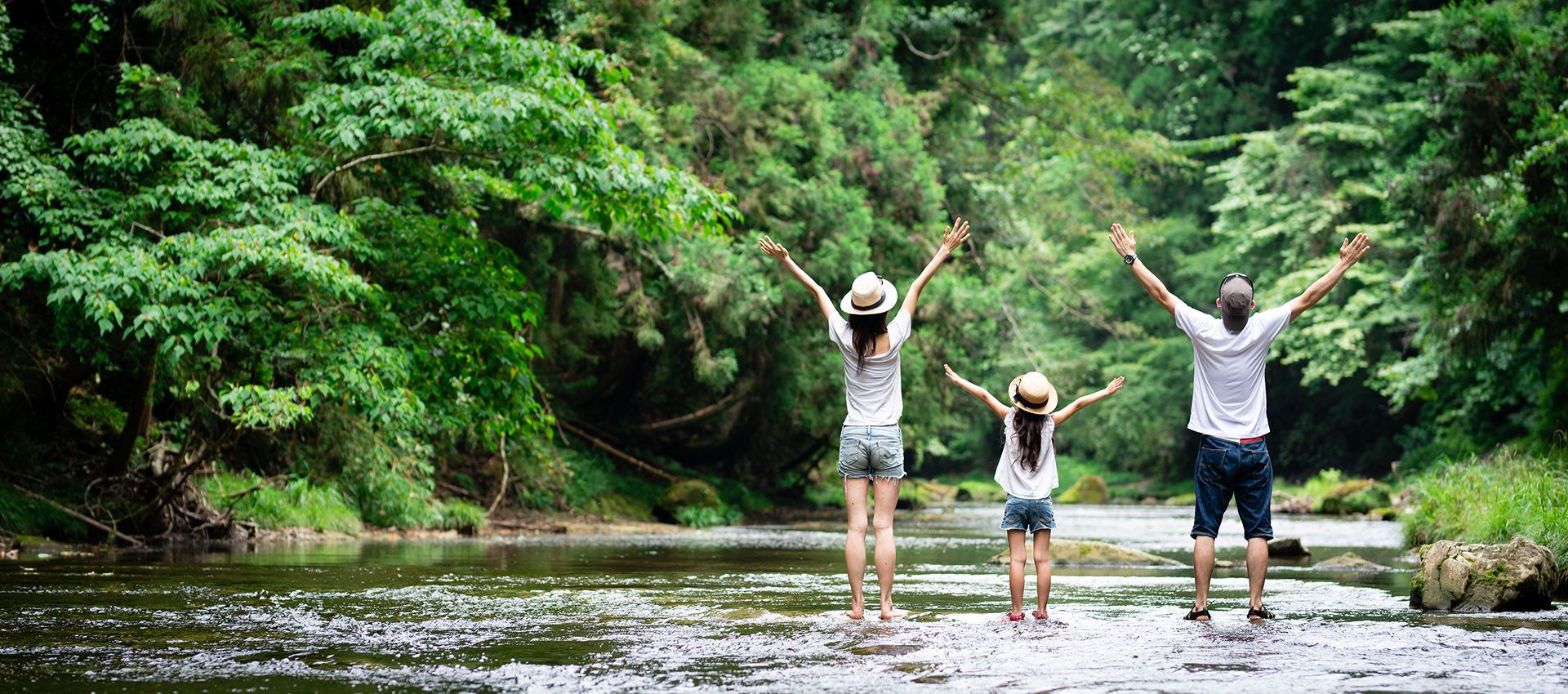 A family is standing in a river with their arms outstretched.