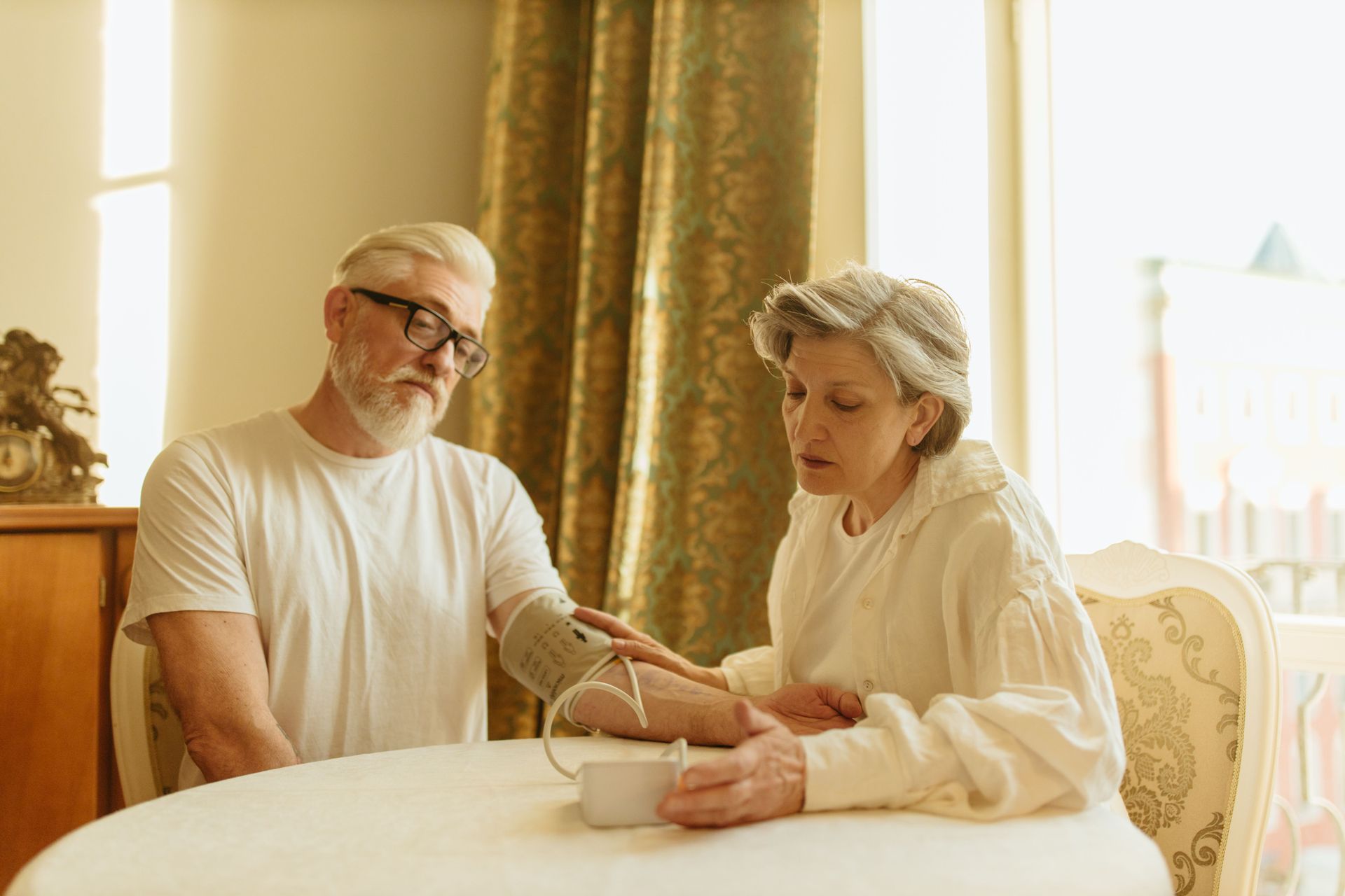 Two people sitting at a table, examining a stethoscope in a bright room