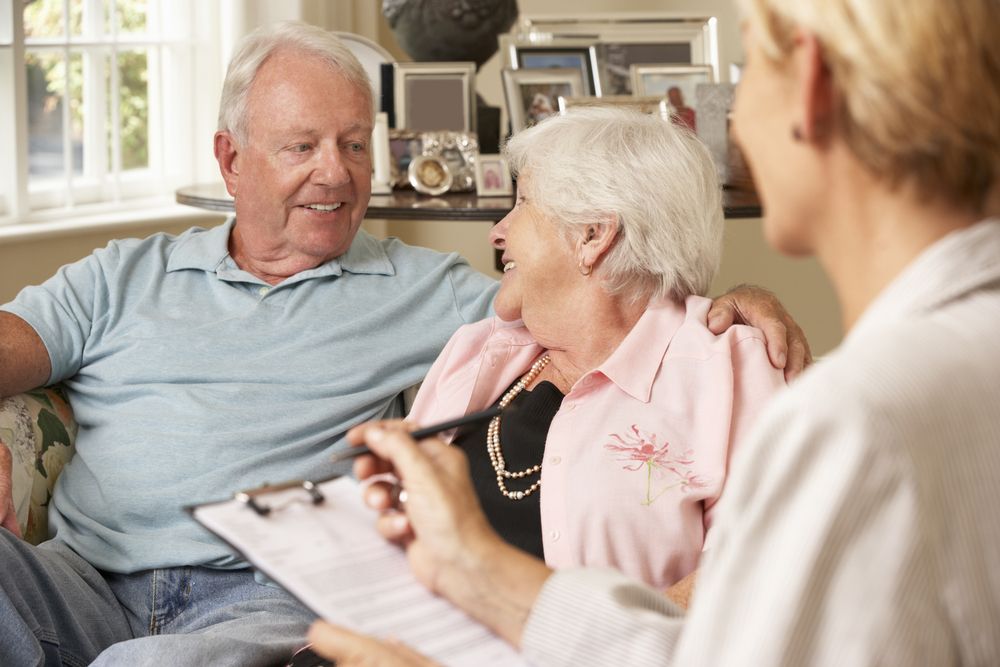 Older couple talking with a caregiver in a bright living room