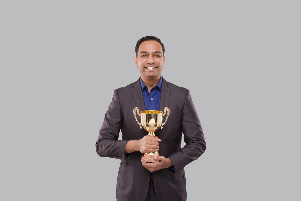 Man On Suit Holding A Trophy — Trophies And Engraving Services In Dapto, NSW