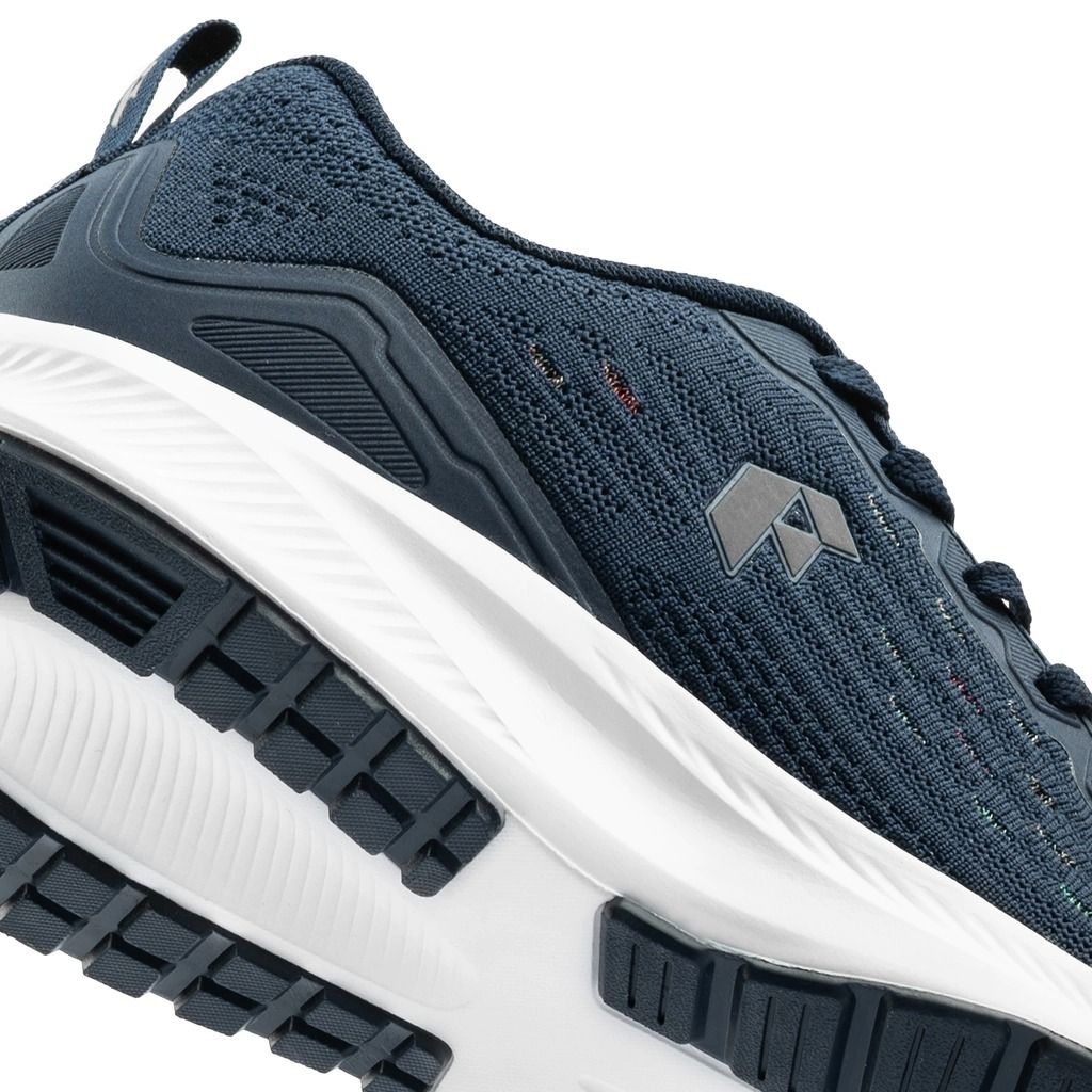 Zapatilla deportiva azul y blanca, vista en ángulo. Parte superior de punto texturizado y suela gruesa y curva.