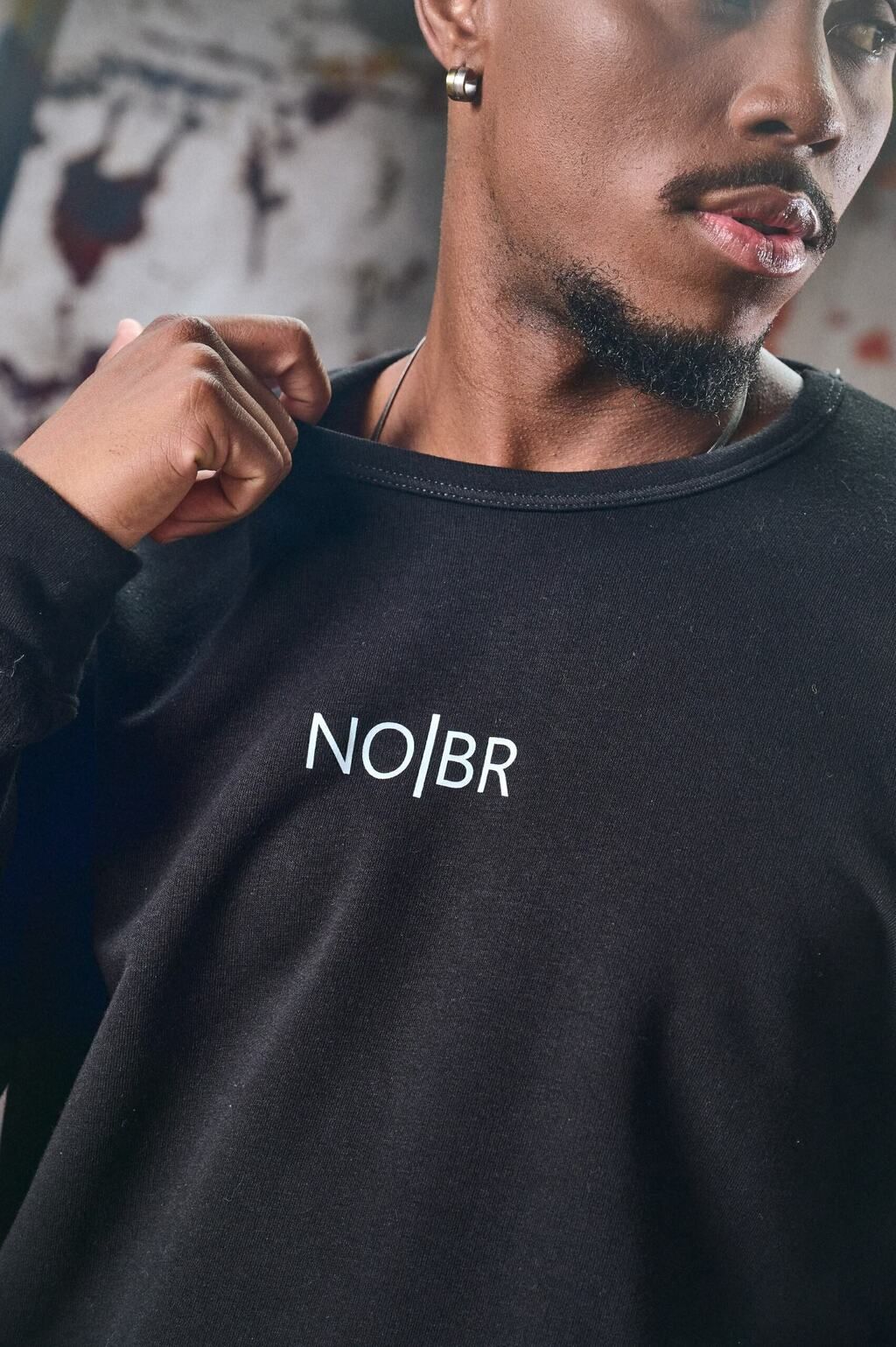 Un hombre con barba lleva una sudadera negra con la palabra no.