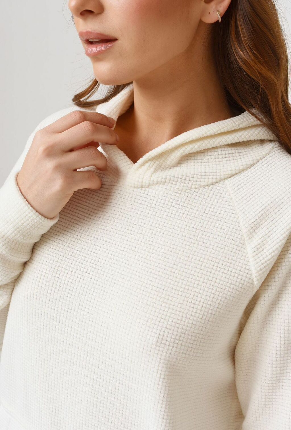 Una mujer lleva una sudadera blanca y pantalones negros.