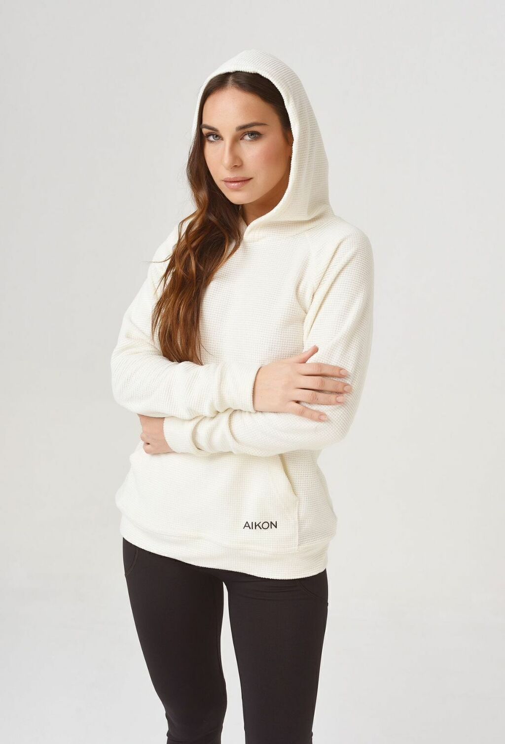 Una mujer lleva una sudadera blanca y pantalones negros.