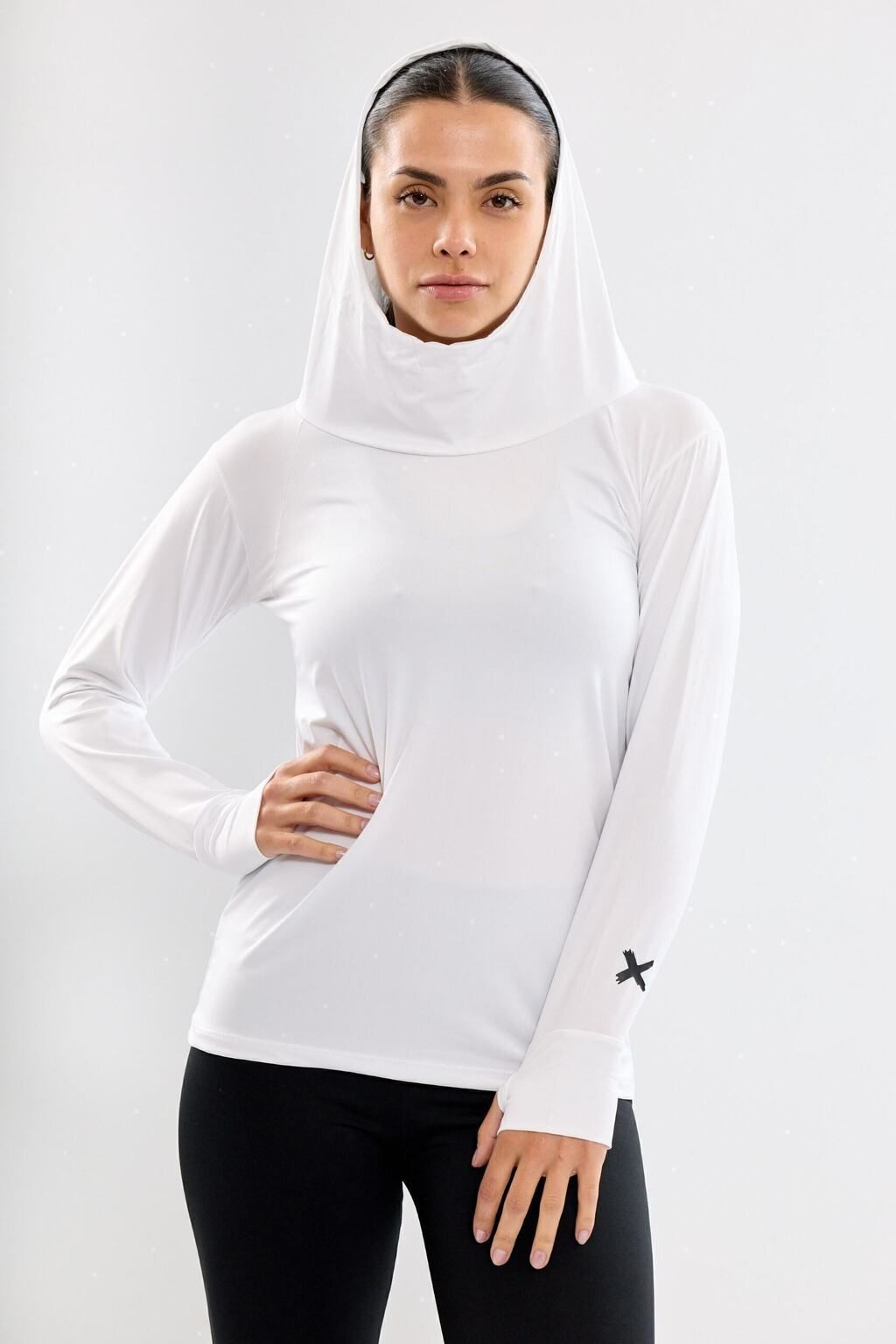 Una mujer lleva una sudadera blanca y pantalones negros.