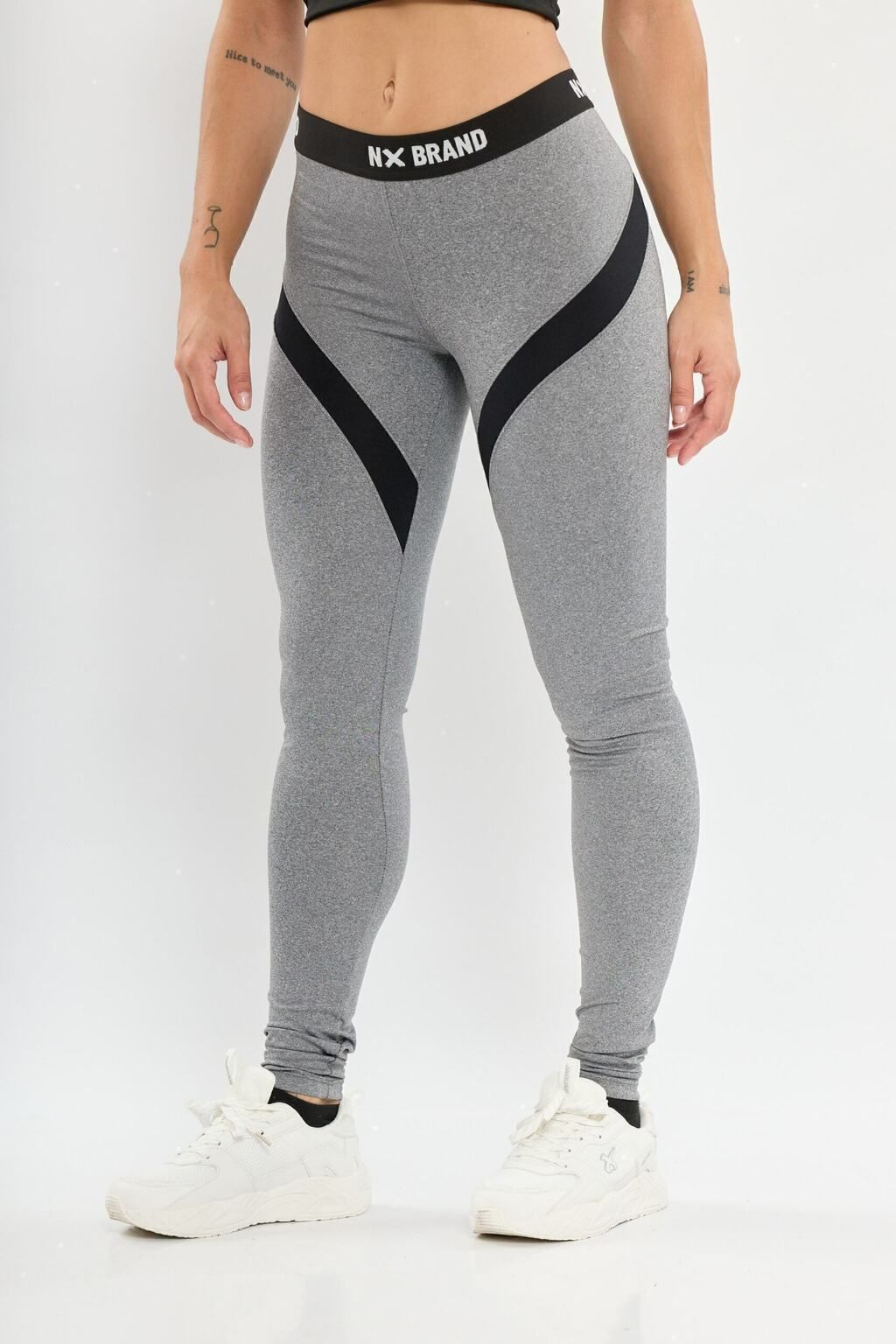 Una mujer lleva un par de leggings grises con rayas negras en los costados.