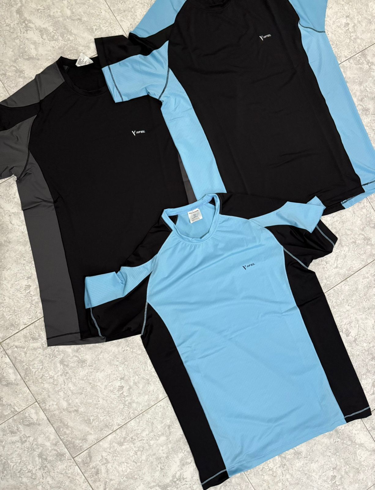 Tres camisetas deportivas: negra y gris, negra y celeste, y celeste y negra.