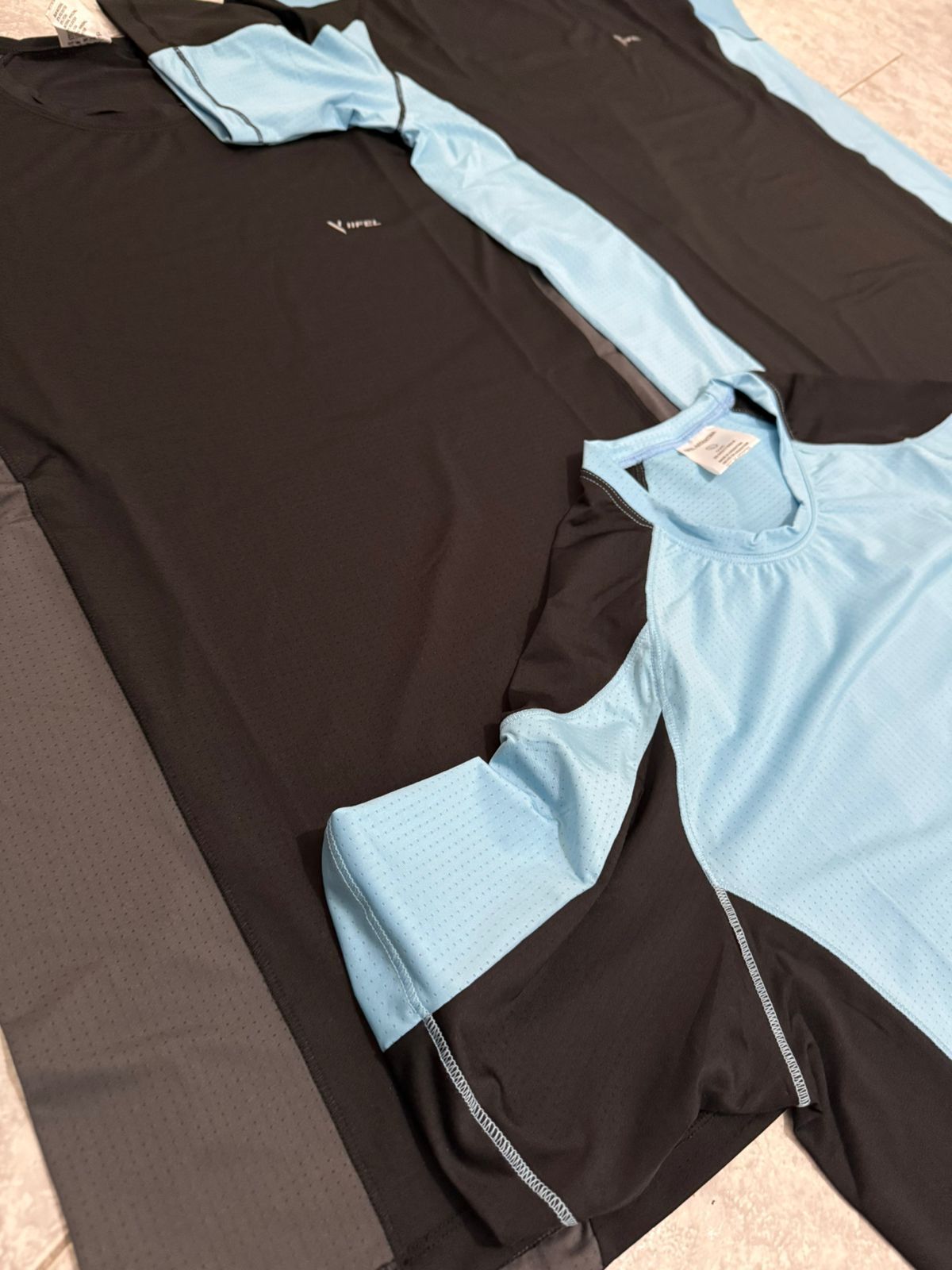 Tres camisetas deportivas: negra y gris, negra y celeste, y celeste y negra.