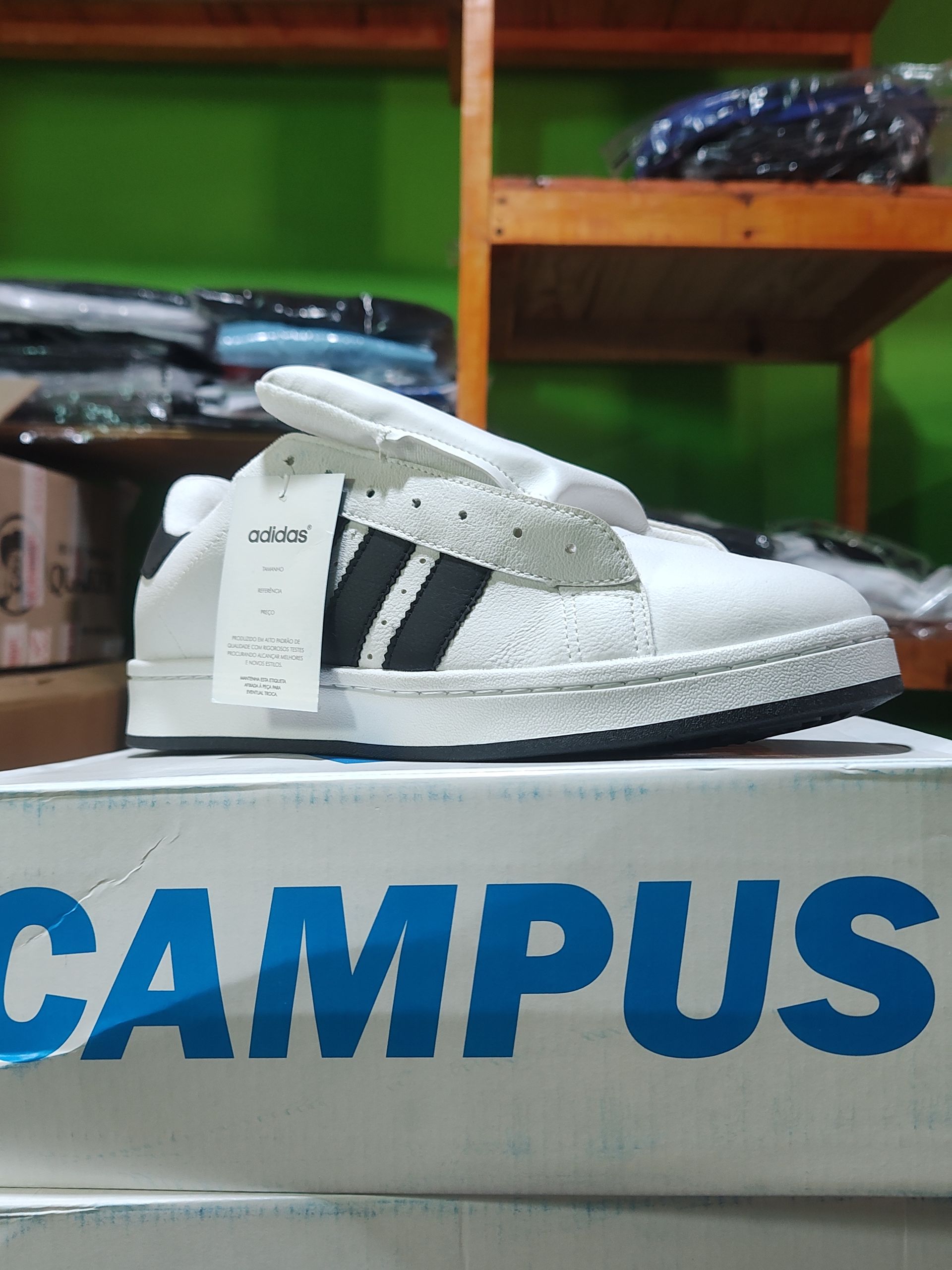 Zapato Campus de color blanco con rayas negras en una caja etiquetada 