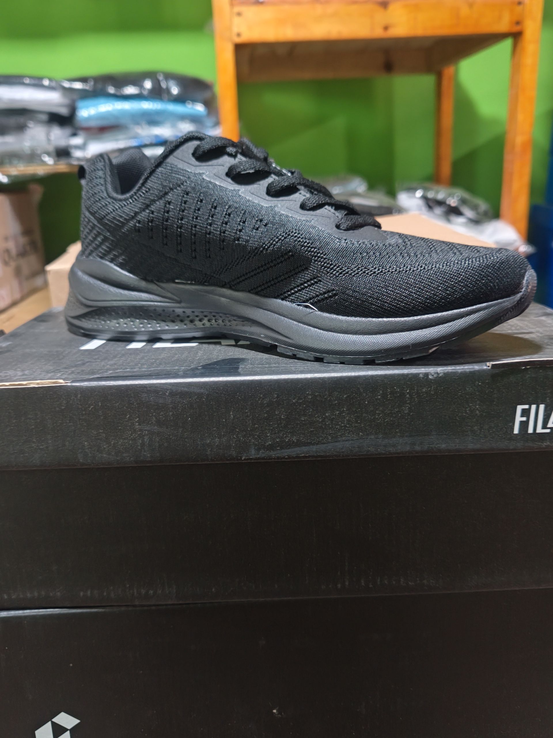 Zapatilla deportiva negra encima de una caja de zapatos negra.