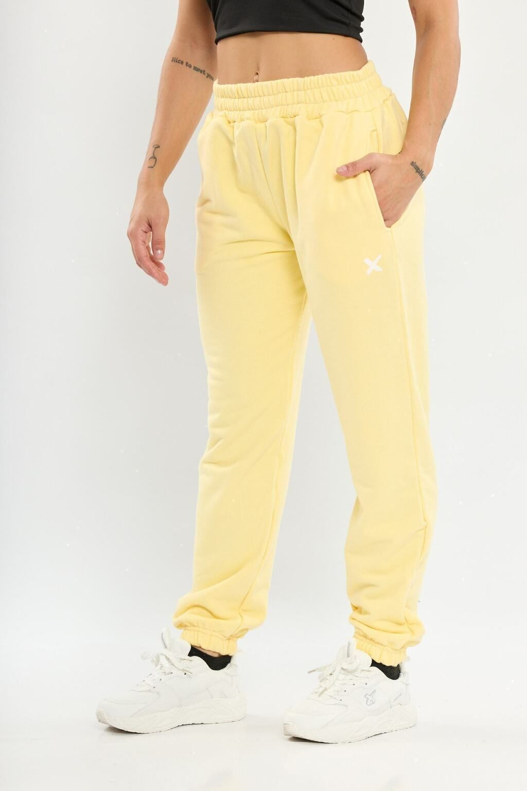 Una mujer lleva un top negro y pantalones deportivos amarillos.