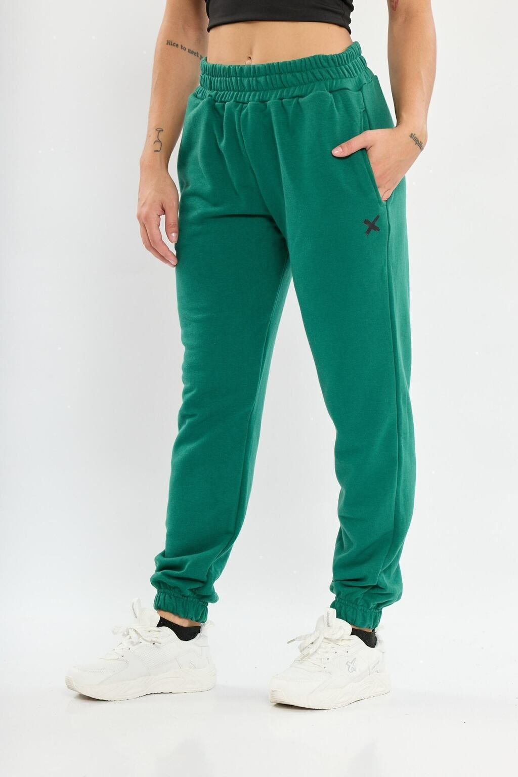 Una mujer lleva pantalones deportivos verdes y zapatillas blancas.