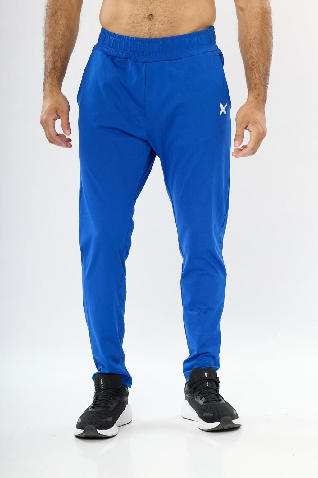 Un hombre lleva pantalones deportivos azules y zapatos negros.