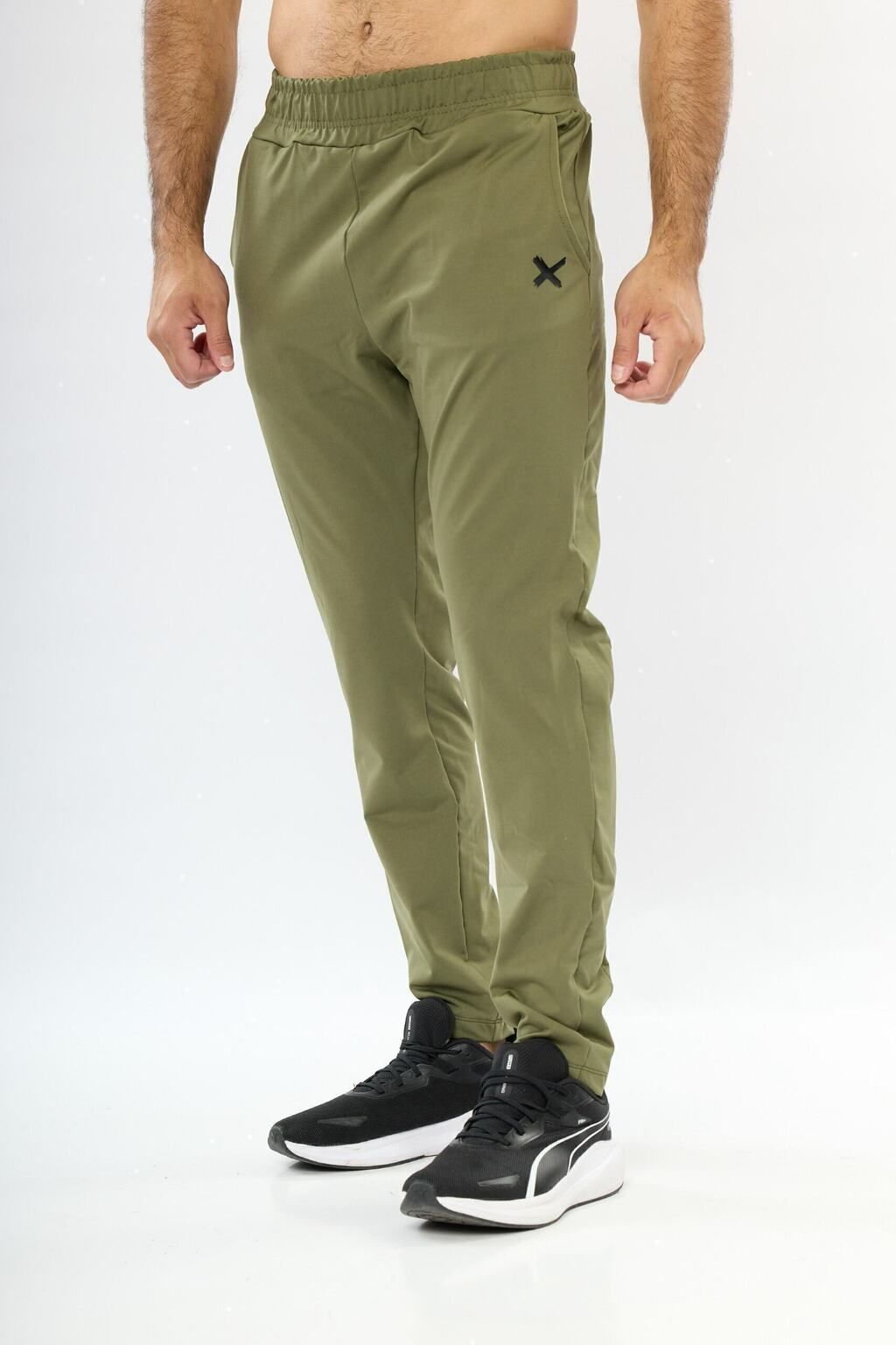 Un hombre lleva un par de pantalones verdes y zapatos negros.