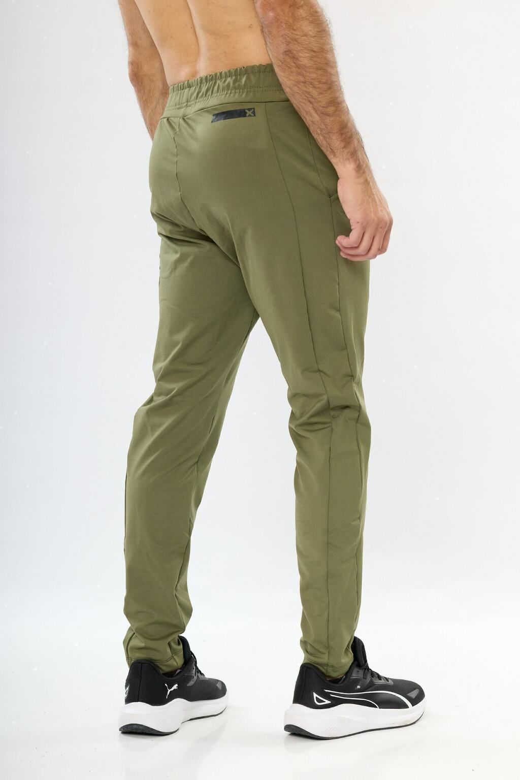 Un hombre lleva un par de pantalones verdes y zapatos negros.