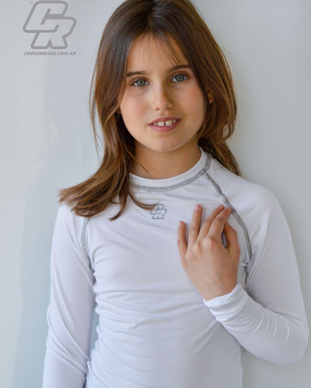 Una niña que lleva una camisa blanca de manga larga con la letra c.