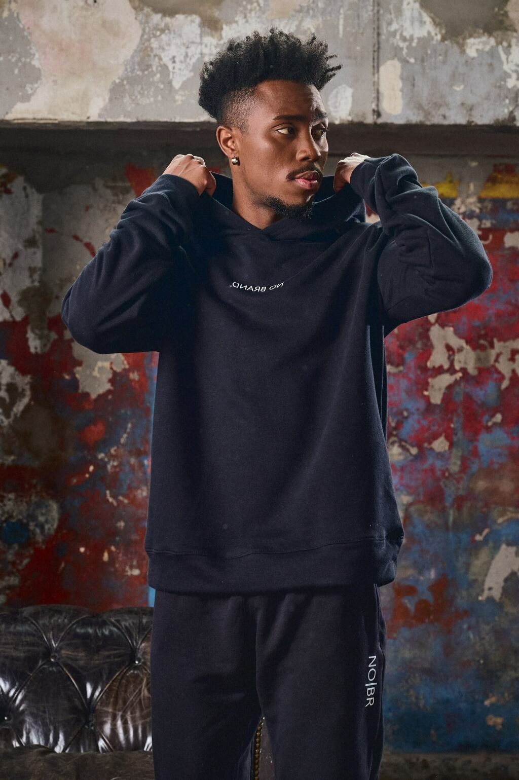 Un hombre que lleva una sudadera con capucha negra se está ajustando la capucha.