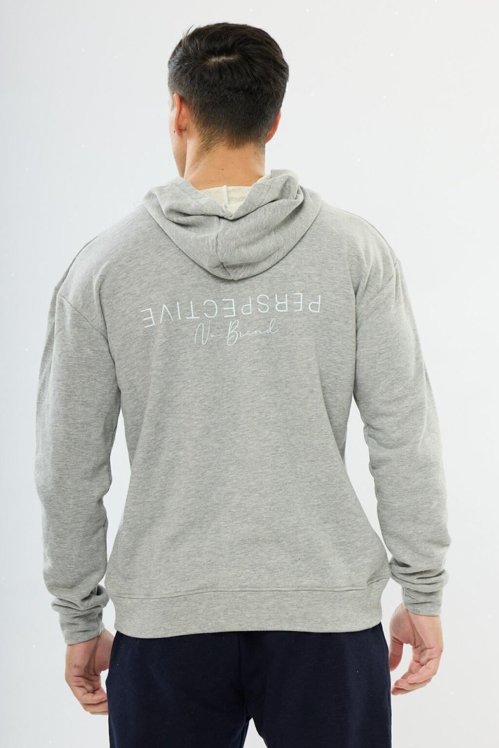 Un hombre lleva una sudadera con capucha gris y pantalones azules.