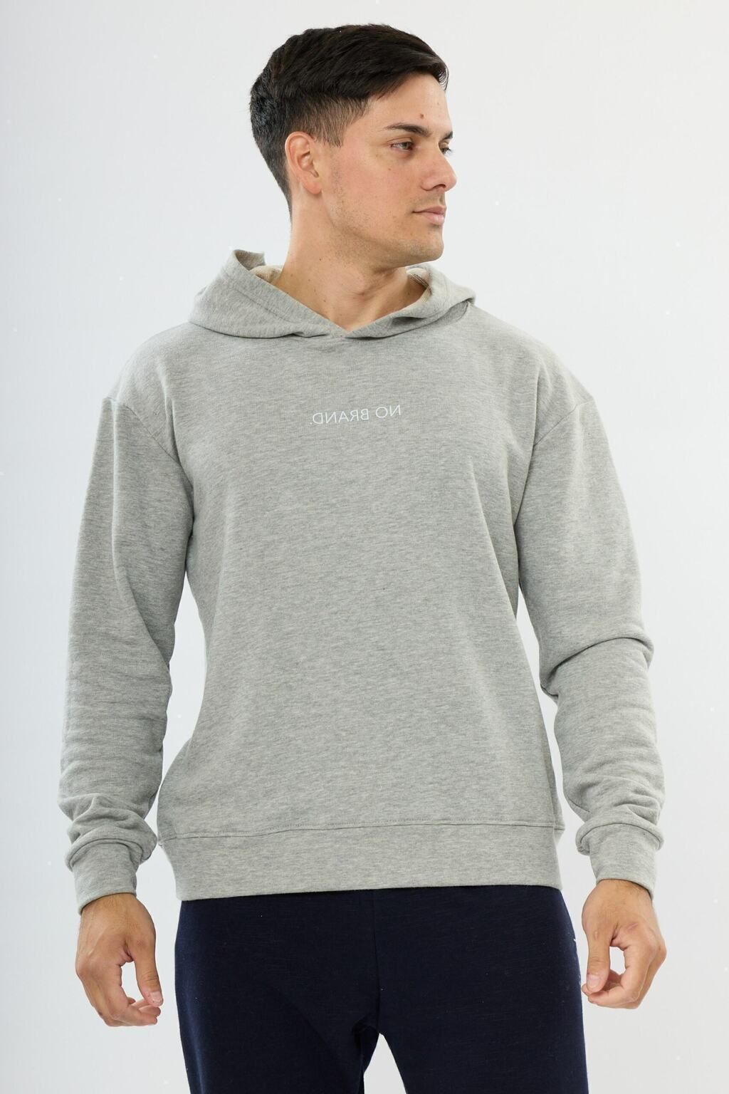 Un hombre lleva una sudadera con capucha gris y pantalones azules.