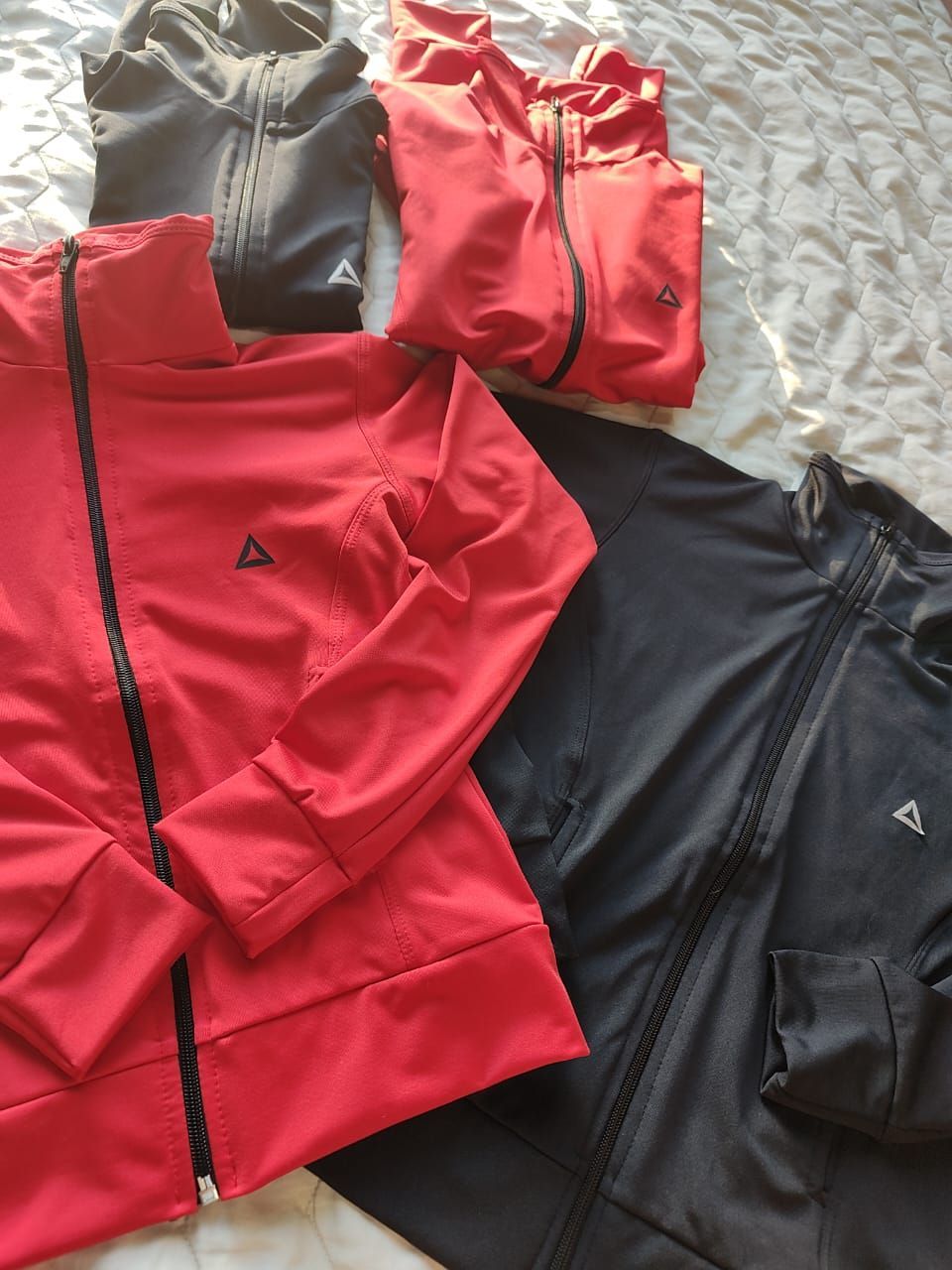 Cuatro chaquetas deportivas con cremallera: dos rojas y dos negras.