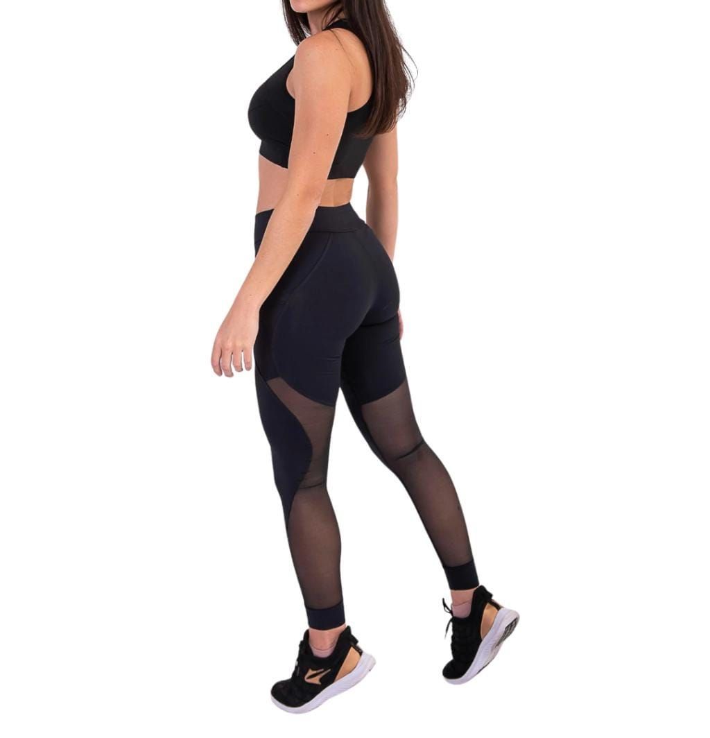 Mujer con leggings negros con paneles de malla y zapatillas negras.