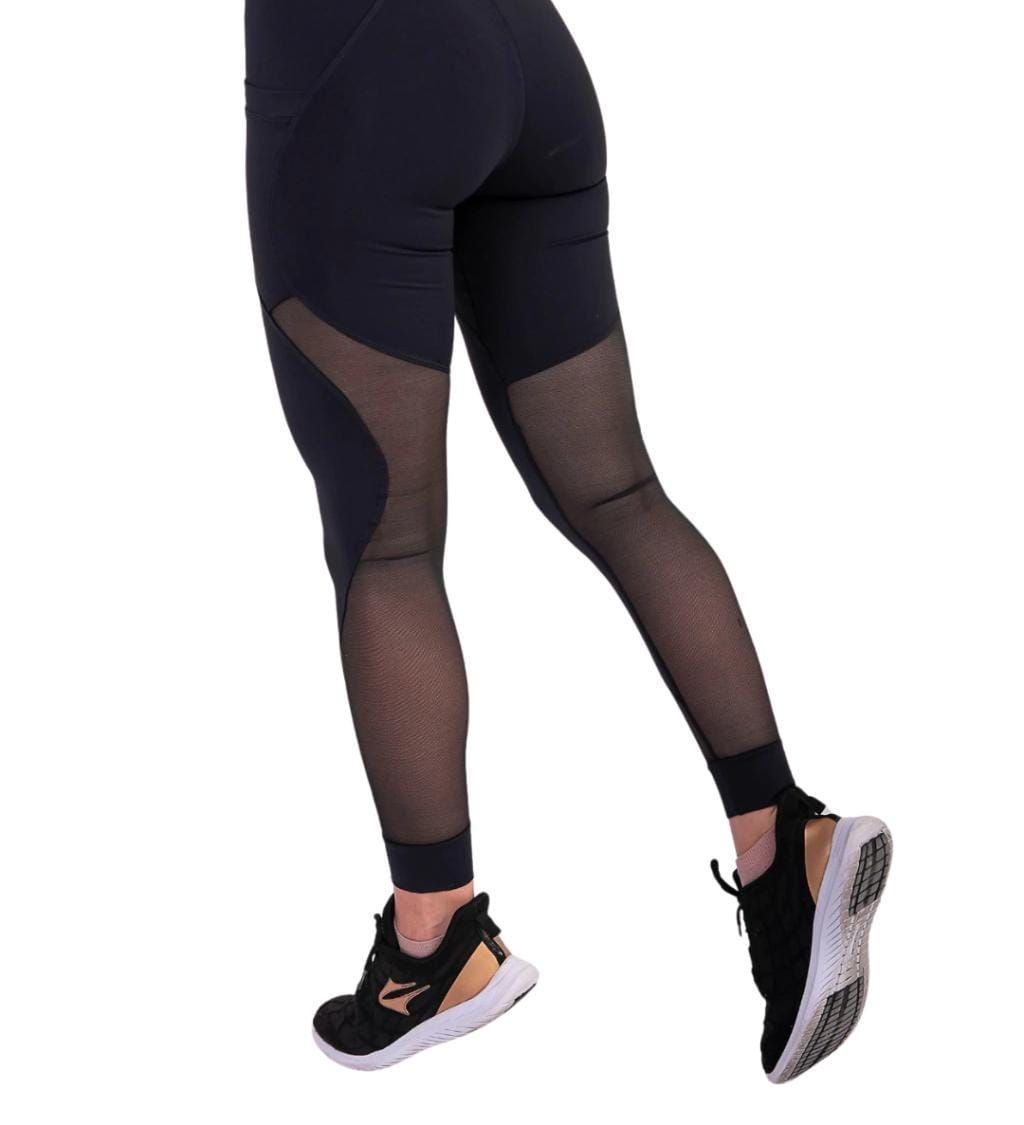 Mujer con leggings negros con paneles de malla y zapatillas negras.