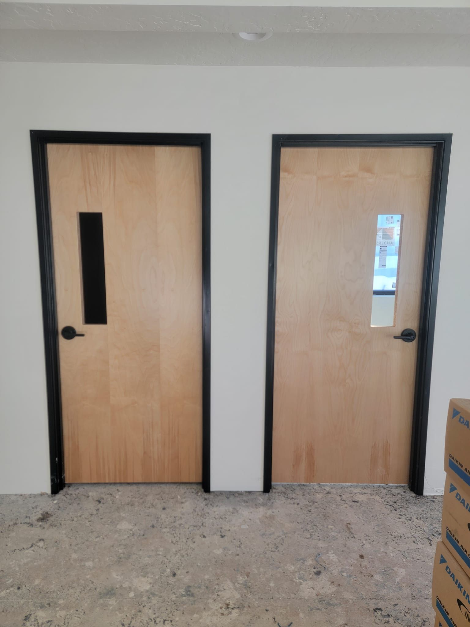 Two wooden doors in a room with boxes on the floor