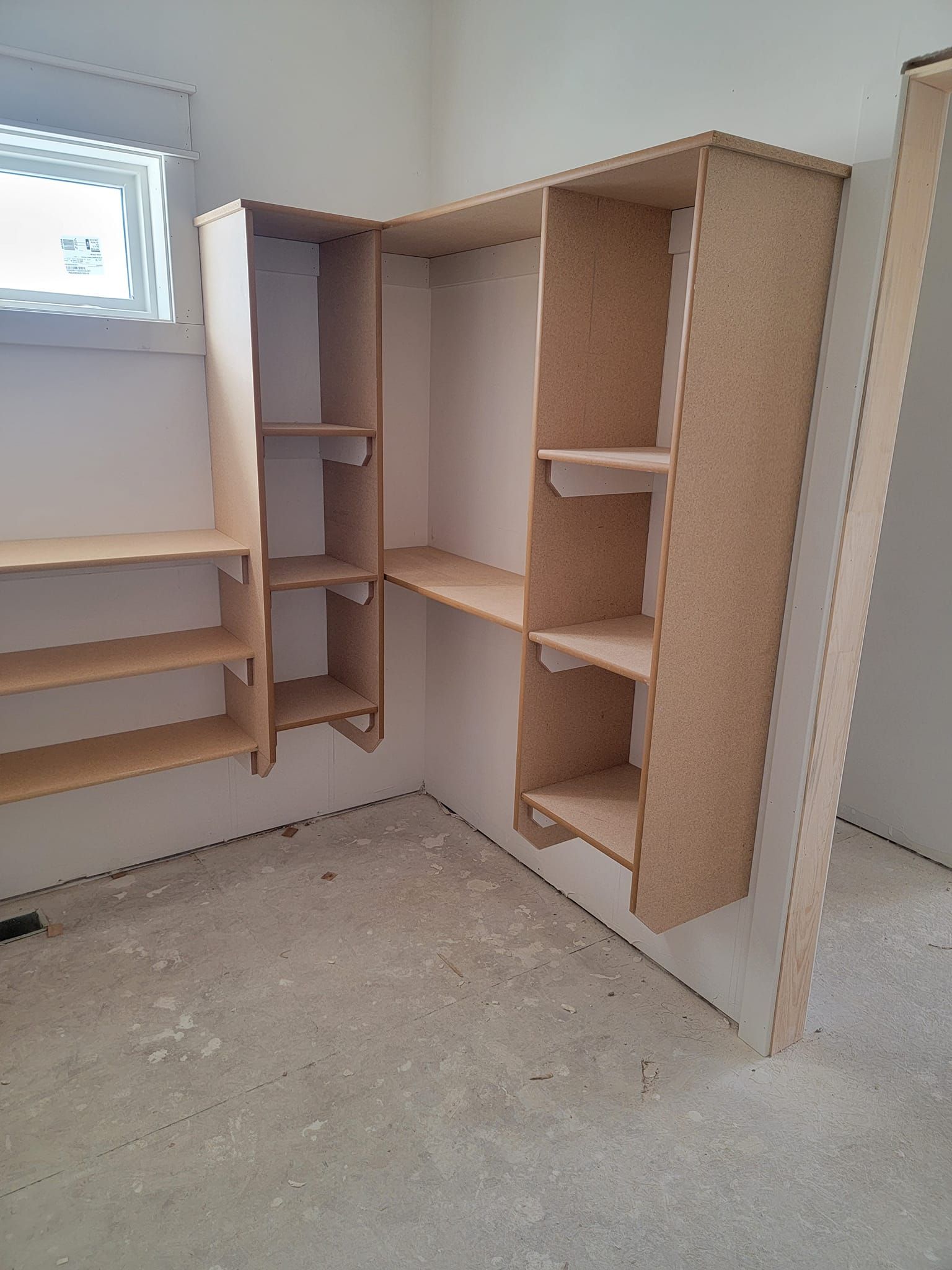 A room with a lot of shelves and a window.