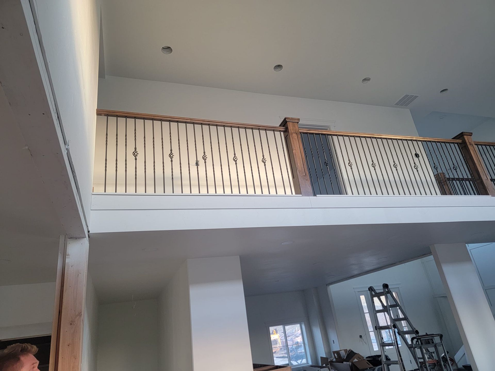 A man is standing on a balcony in a house under construction.