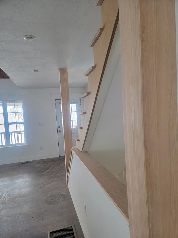 A living room with a wooden staircase and a window.
