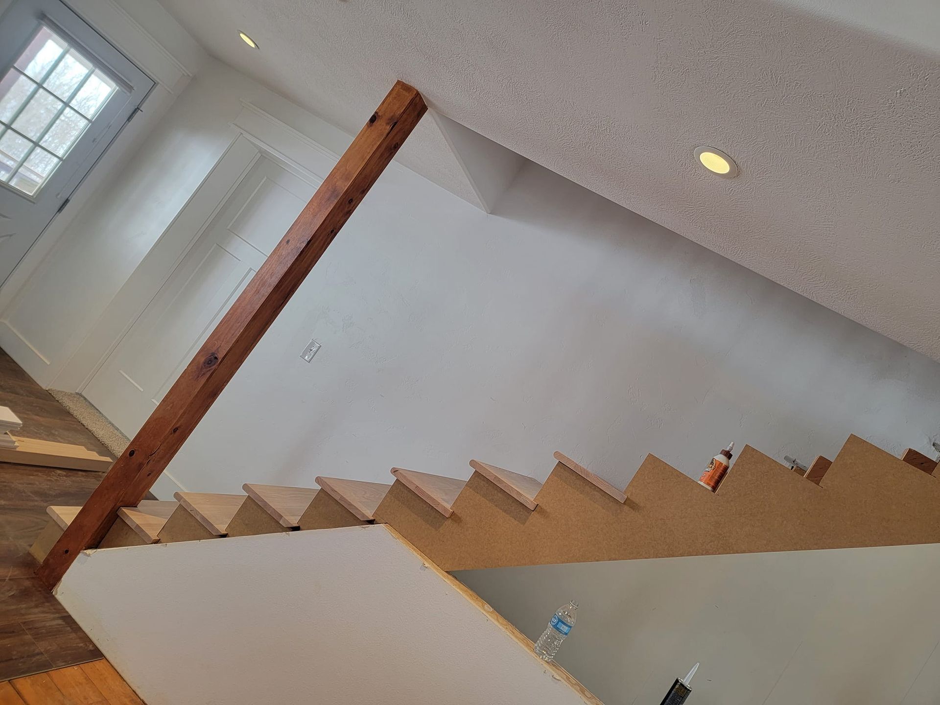 A staircase in a house with a wooden railing and a white wall.