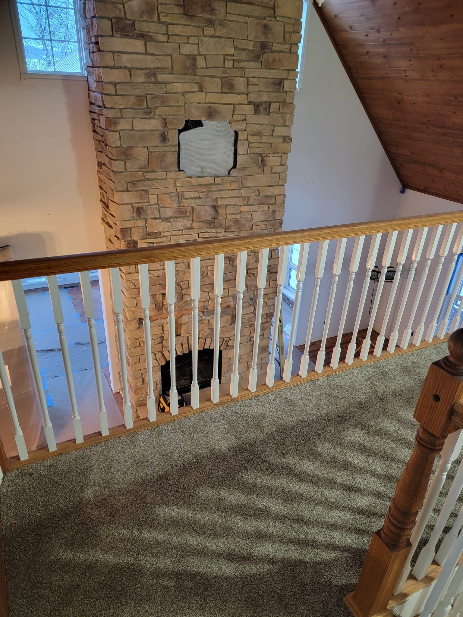 A cat is sitting on a staircase next to a stone fireplace.