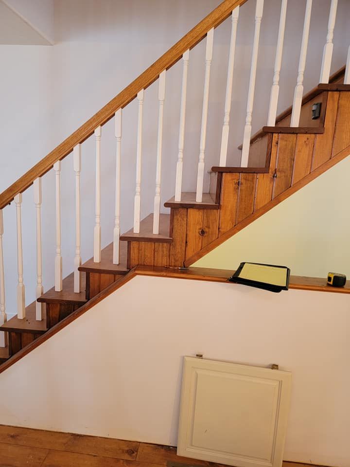 A wooden staircase with white railings and a white door