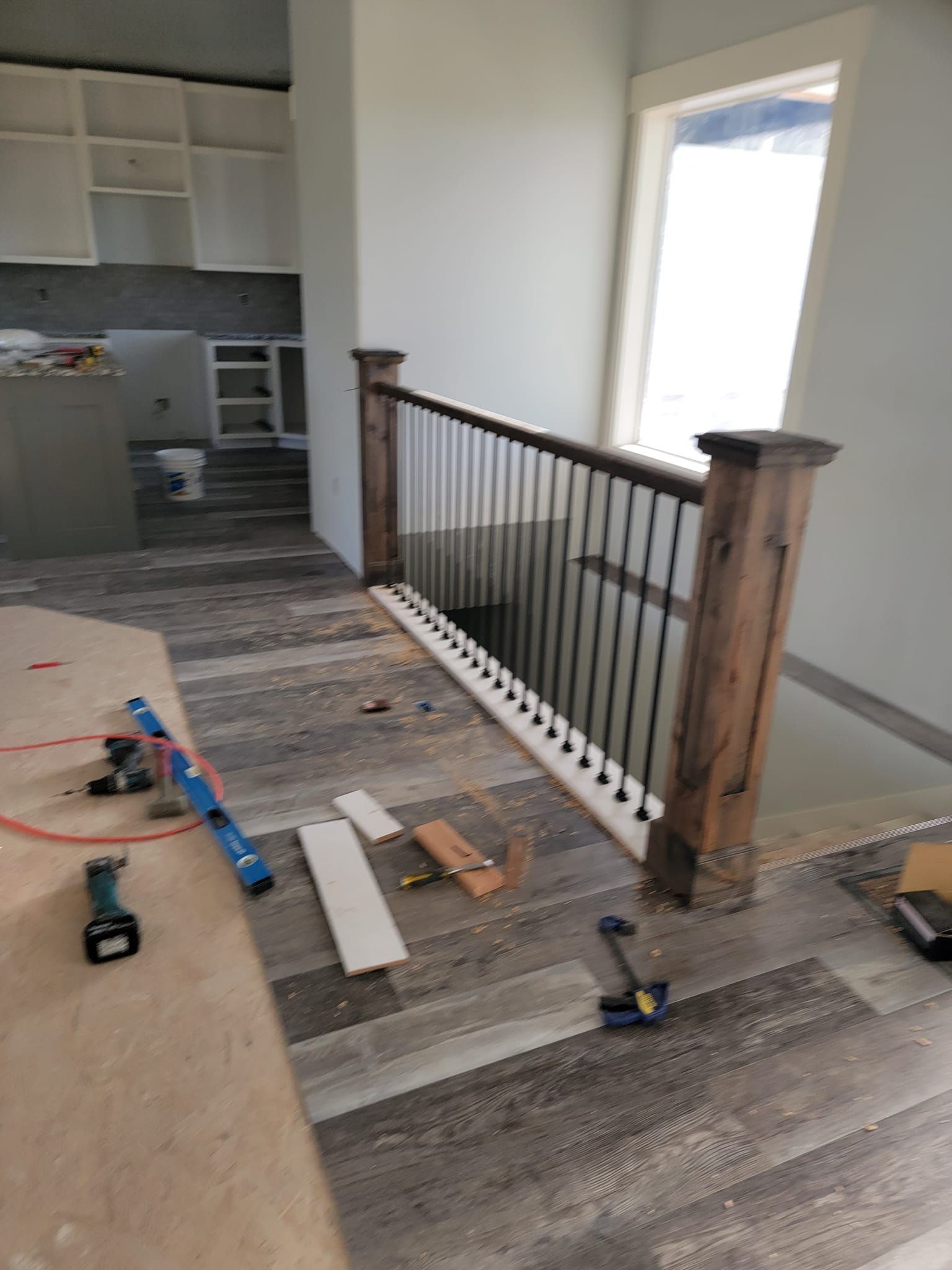 A wooden railing is being installed on a staircase in a house under construction.