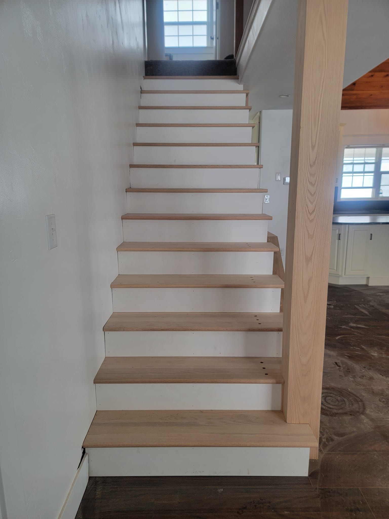 A white staircase with wooden steps in a house.