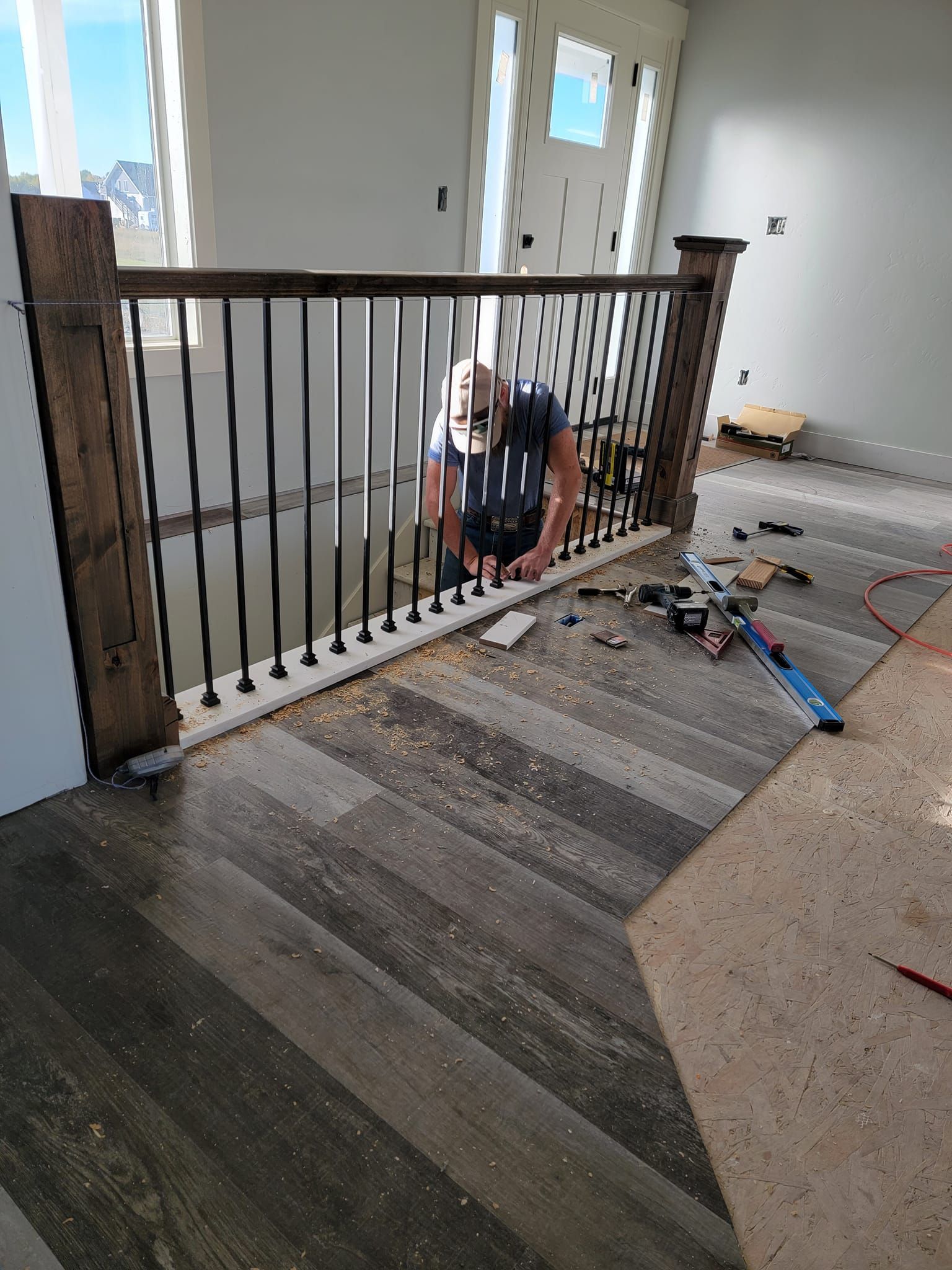 A man is working on a wooden railing on a staircase.