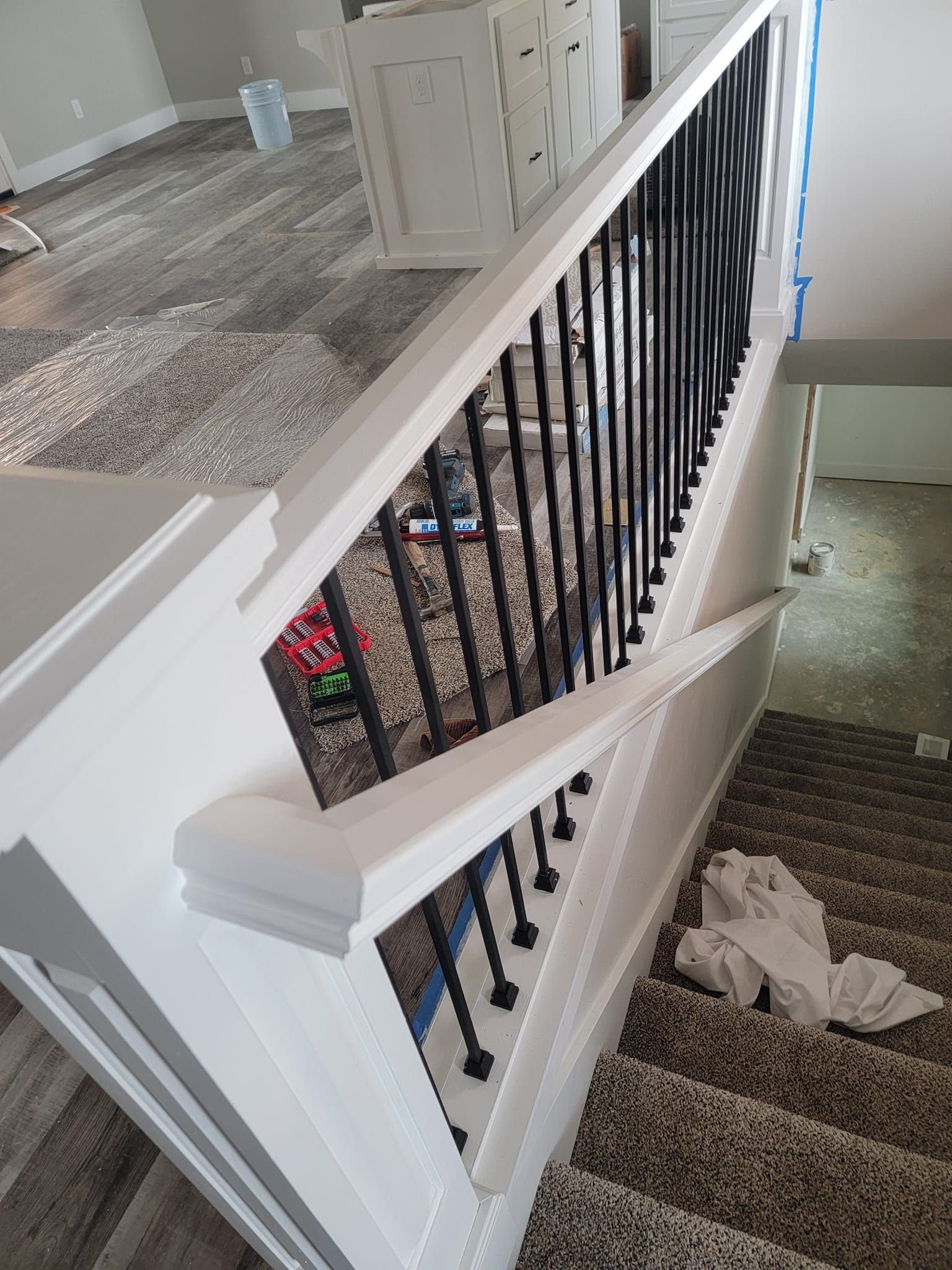 A staircase with a white railing and a black railing in a living room.