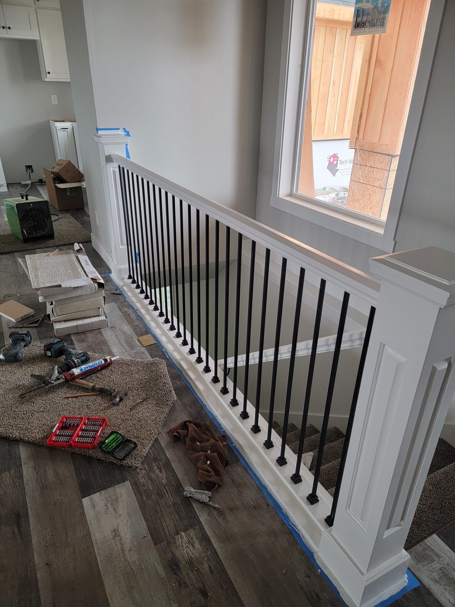 A white railing with black bars is sitting next to a window in a room.