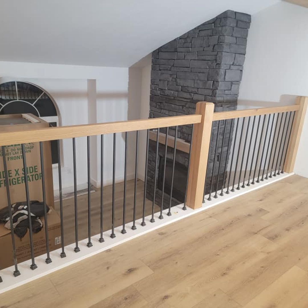 A wooden staircase with a metal railing and a brick fireplace.