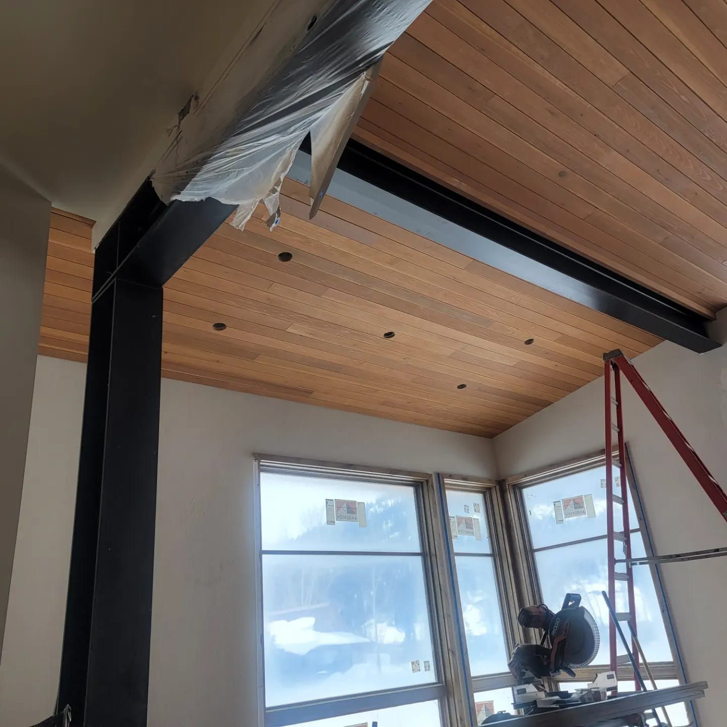 A room with a wooden ceiling and lots of windows