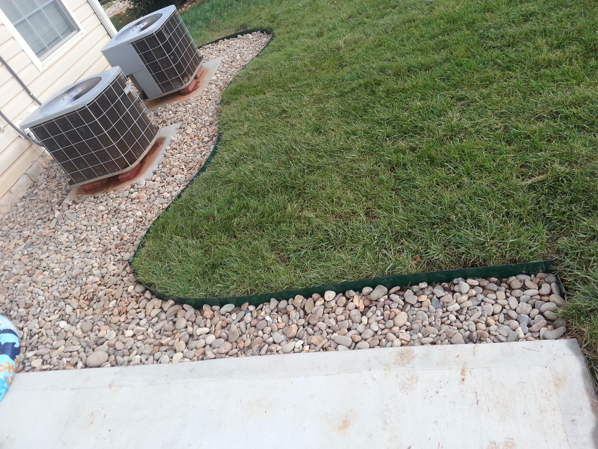Two air conditioners are sitting on top of a lush green lawn wellford 