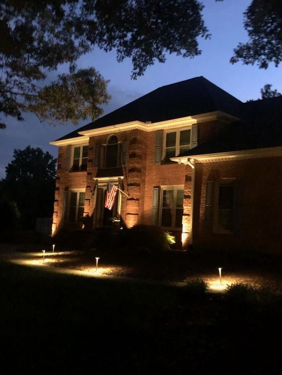 A large brick house is lit up at night.