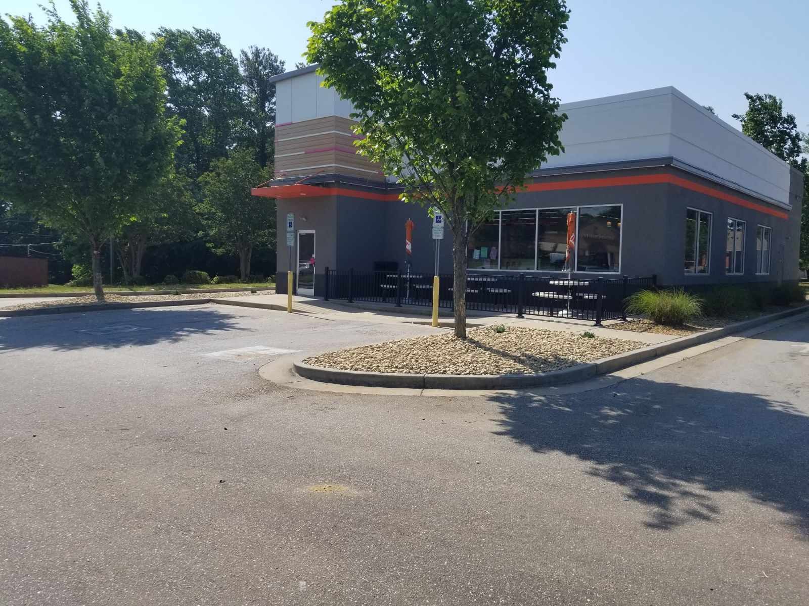 A fast food restaurant with a parking lot in front of it.