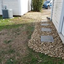 A house with a walkway leading to it and a car parked in the background.