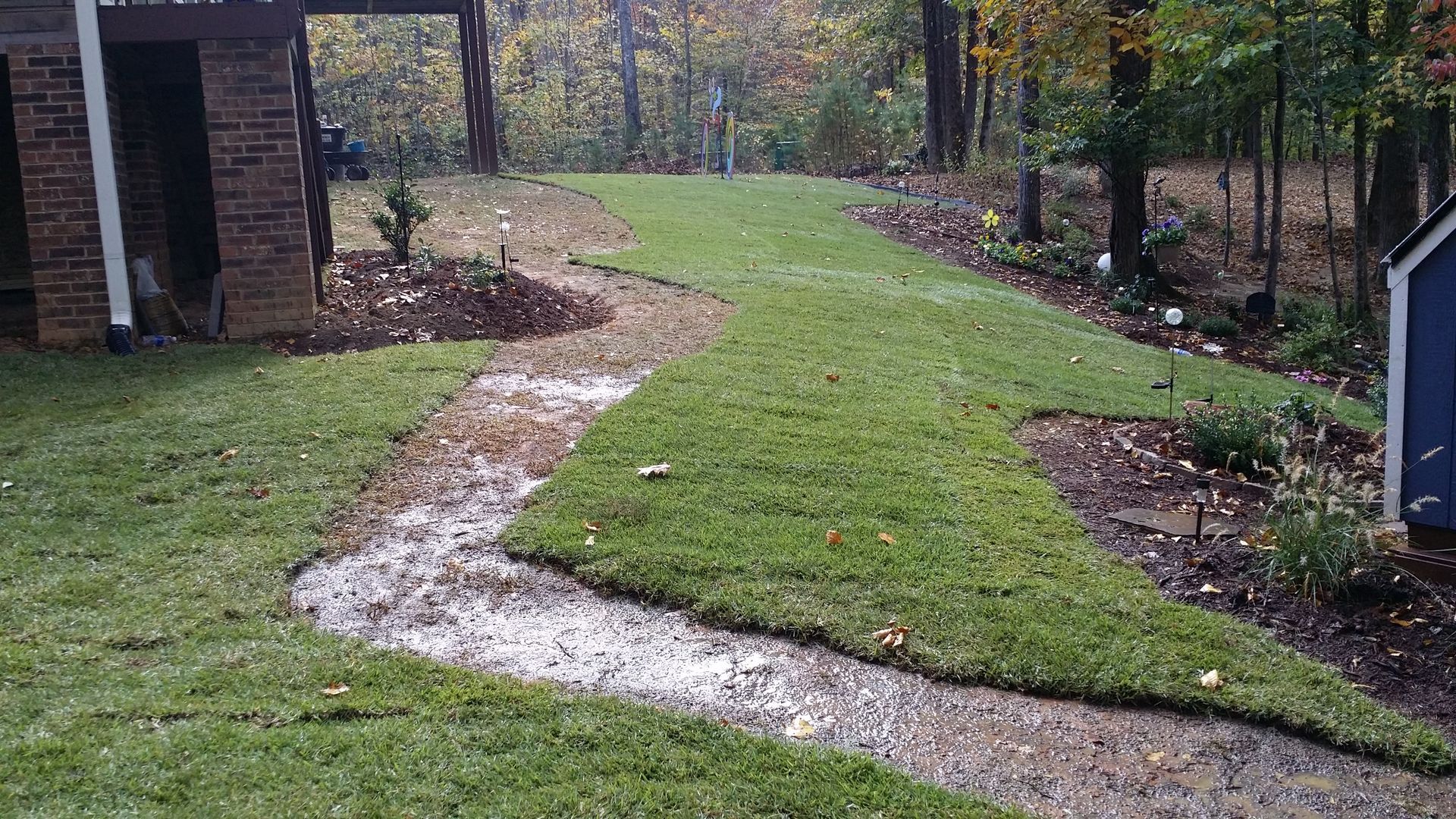 A lush green lawn with a dirt path leading to a house woodruff 