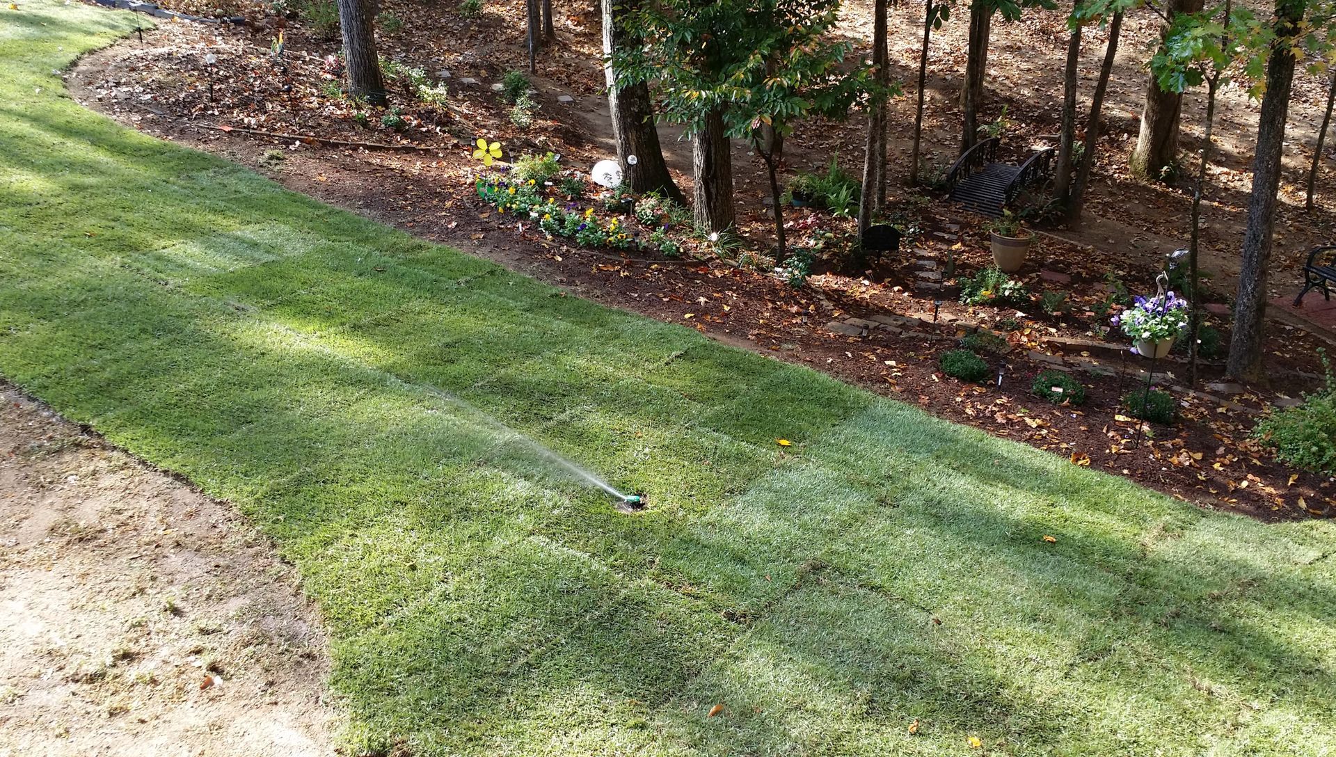 A lawn sprinkler is spraying water on a lush green lawn woodfin