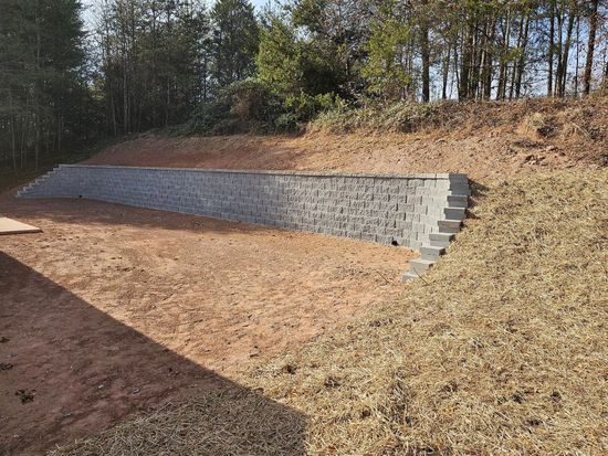 A stone wall with stairs leading up to it is sitting on top of a dirt hill.