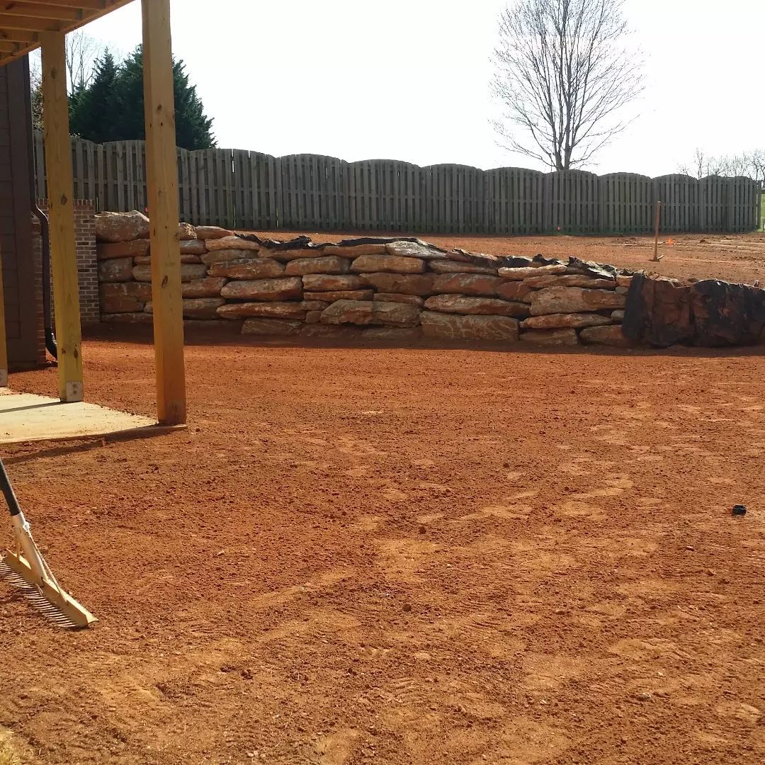 There is a fence in the background and a pile of dirt in the foreground.